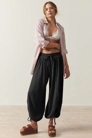 Black balloon trousers with drawstring waist and ankle ties, styled with a striped shirt.