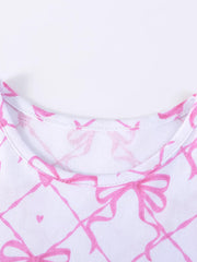 Baby dress with pink bow and heart print on white cotton fabric.