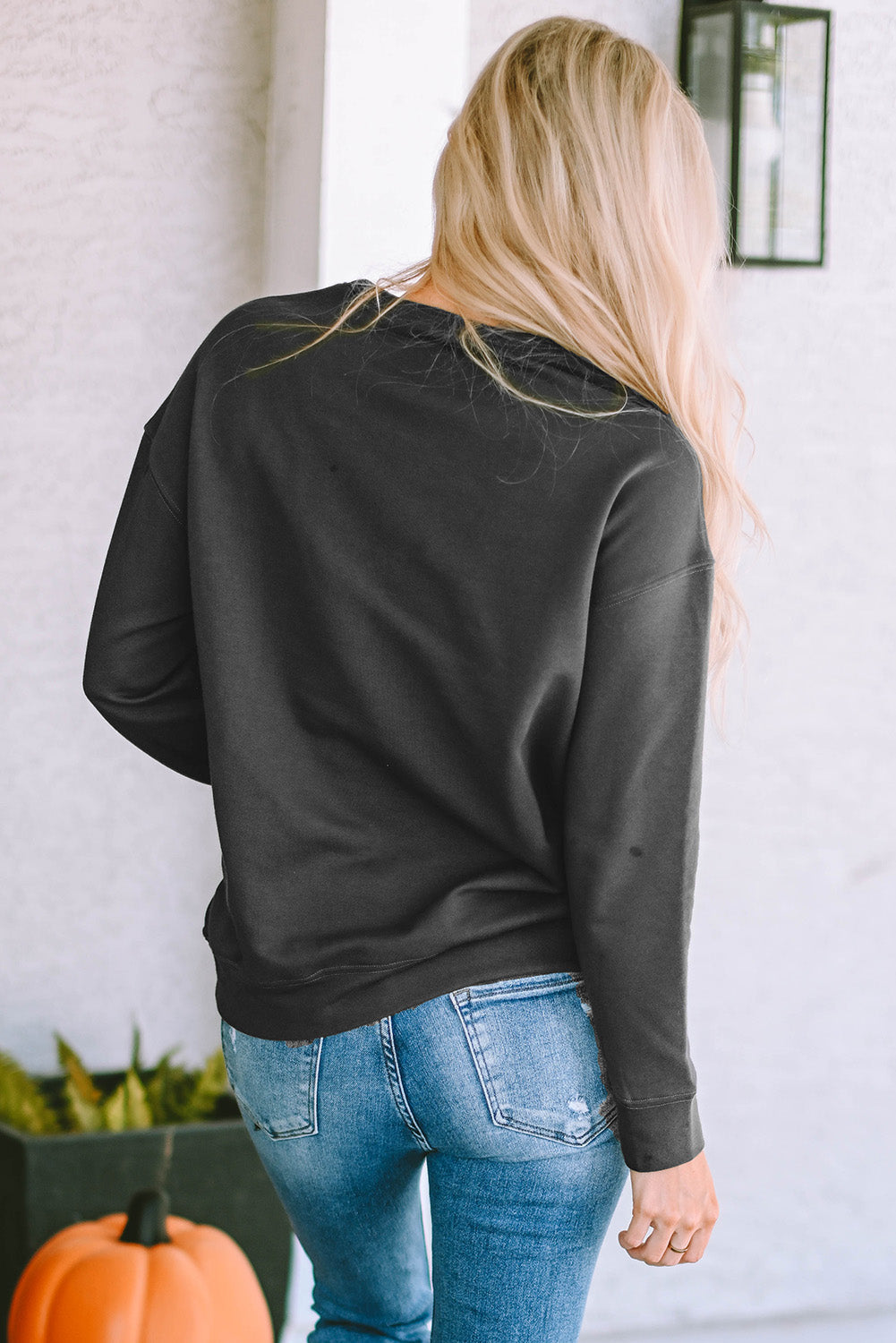 Charcoal crewneck sweatshirt with long sleeves, styled with distressed jeans.