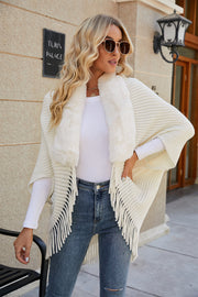 Ivory knit cape with faux fur collar and fringe detail.