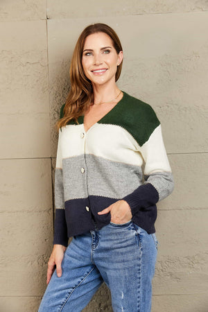 Colorblock acrylic cardigan with metallic trim in green, white, grey, and navy.