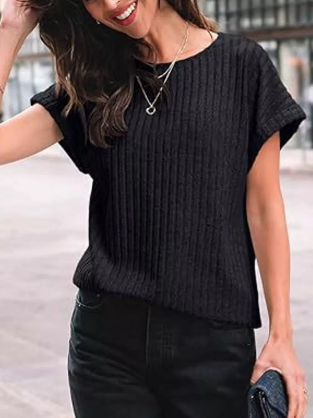 Black ribbed knit t-shirt with short sleeves and a crew neck, styled with jeans.
