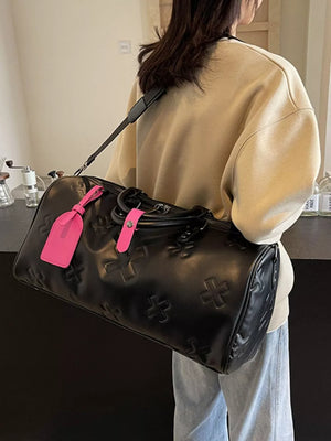 Black embossed cross detail luxury duffel bag with pink luggage tags.