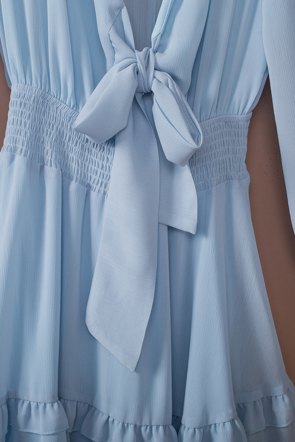 Sky blue ruffled mini dress with smocked waist and bow-tie neckline.