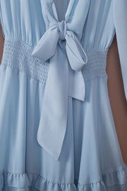 Sky blue ruffled mini dress with smocked waist and bow-tie neckline.