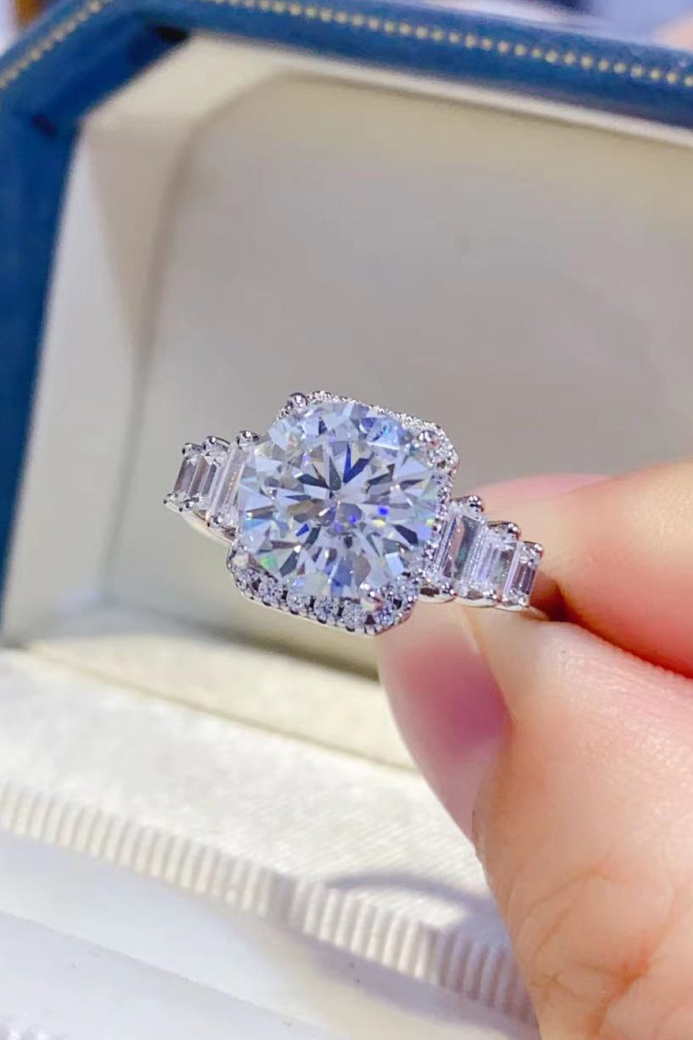 Cushion cut moissanite and baguette ring in silver with halo detail.