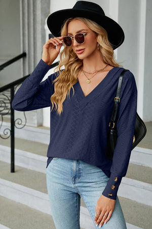 Dark blue V-neck blouse with diamond texture and button cuff detail.