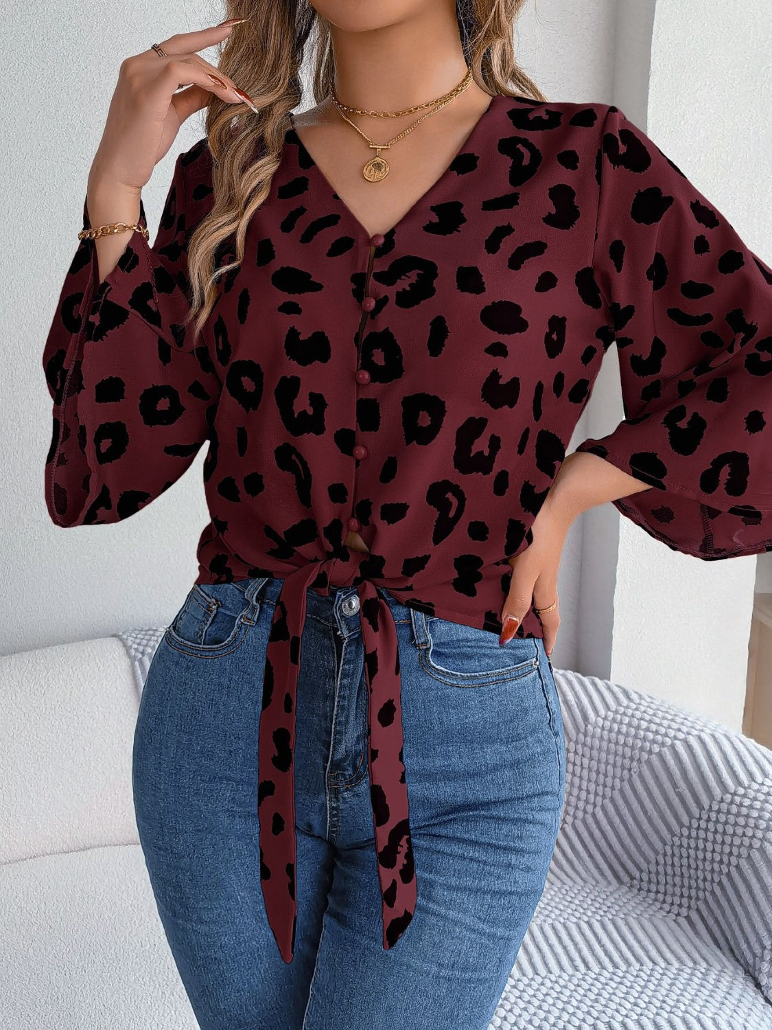 Burgundy leopard print tie-front blouse with button detail and bell sleeves.