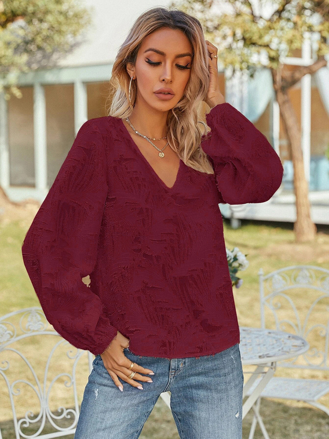 Burgundy textured puff sleeve V-neck blouse with full-length sleeves.