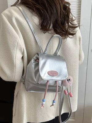 Silver leather mini drawstring backpack with beaded accents and a fluffy charm.