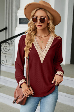 Burgundy textured V-neck blouse with lace trim on neckline and cuffs.