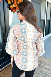 Geometric print blouse with tassel tie in floral colors, featuring balloon sleeves.