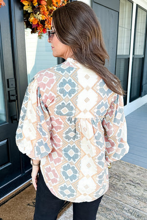 Geometric print blouse with tassel tie in floral colors, featuring balloon sleeves.