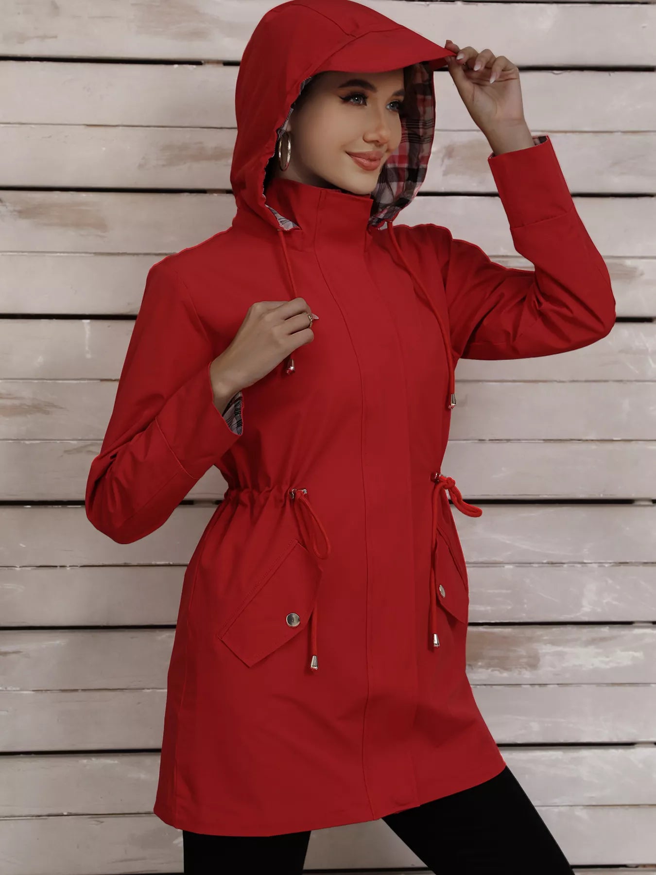 Red drawstring trench coat with hood and plaid lining, featuring snap pockets.