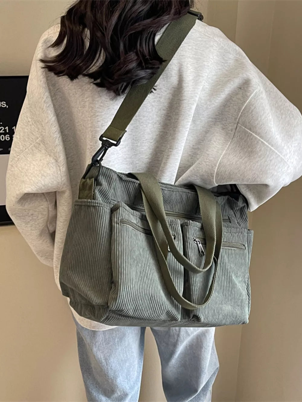 Green corduroy crossbody bag with multiple zippered pockets and adjustable strap.