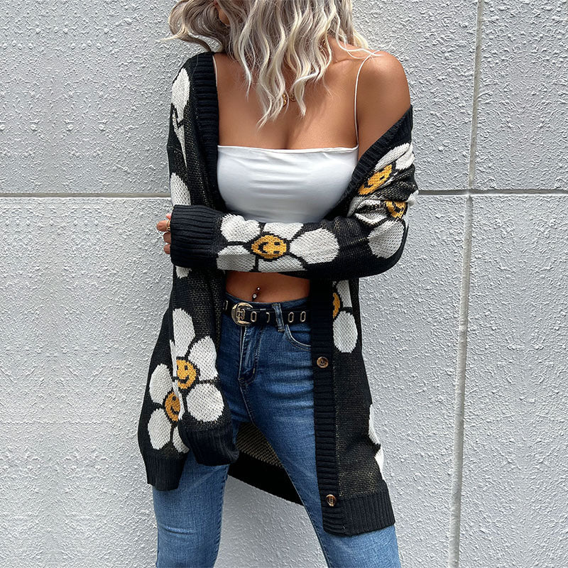 Black intarsia knit cardigan with daisy smile pattern, button front, and long sleeves.