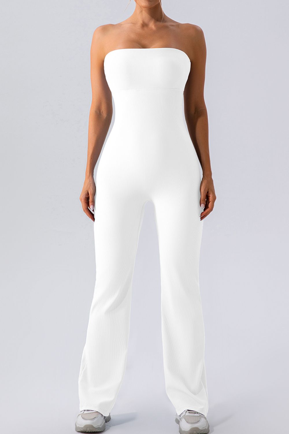White ribbed bandeau flare leg jumpsuit with a seamless bodice and athletic shoes.