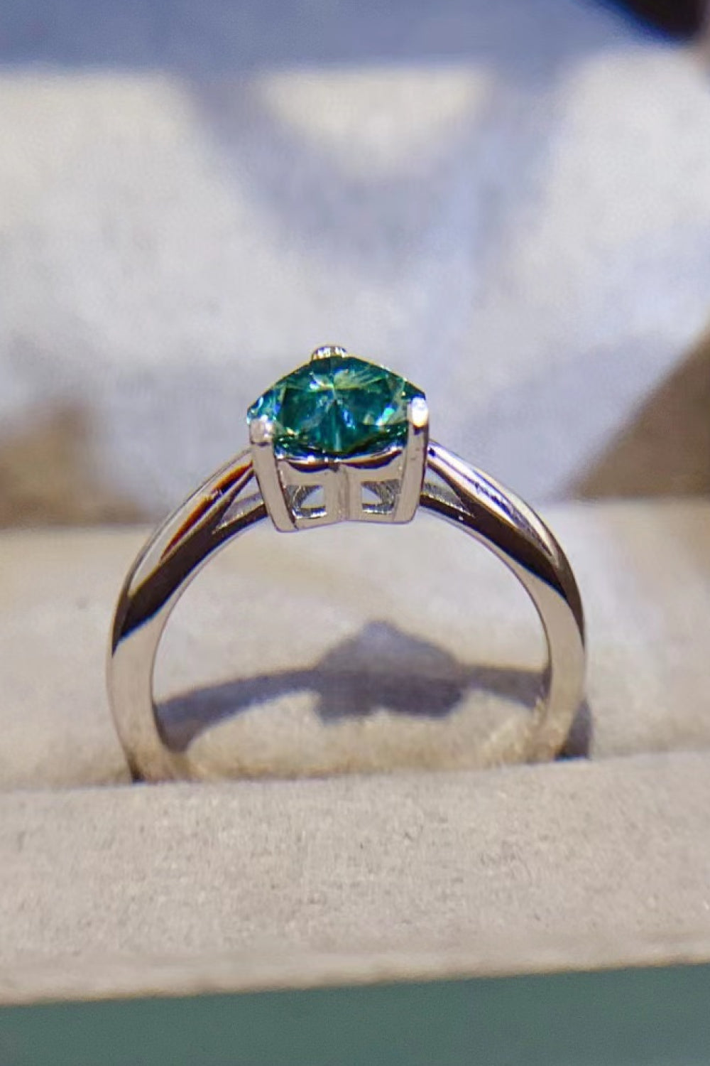 Green moissanite solitaire ring with a silver band.