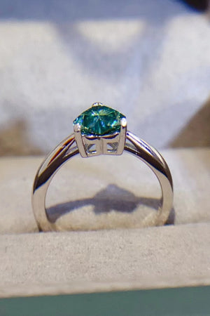 Green moissanite solitaire ring with a silver band.