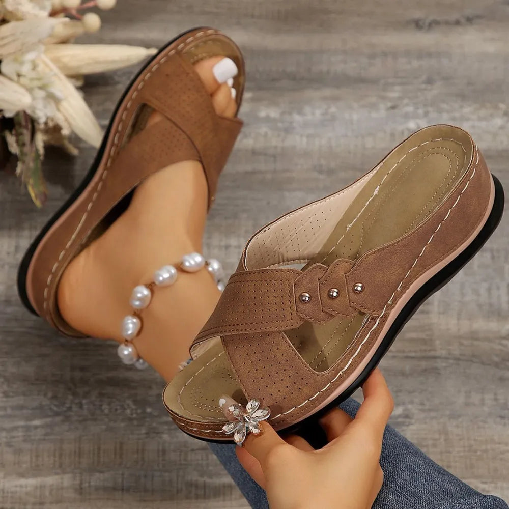 Camel perforated cross-strap comfort sandals with adjustable buckle detail and flower embellishment.