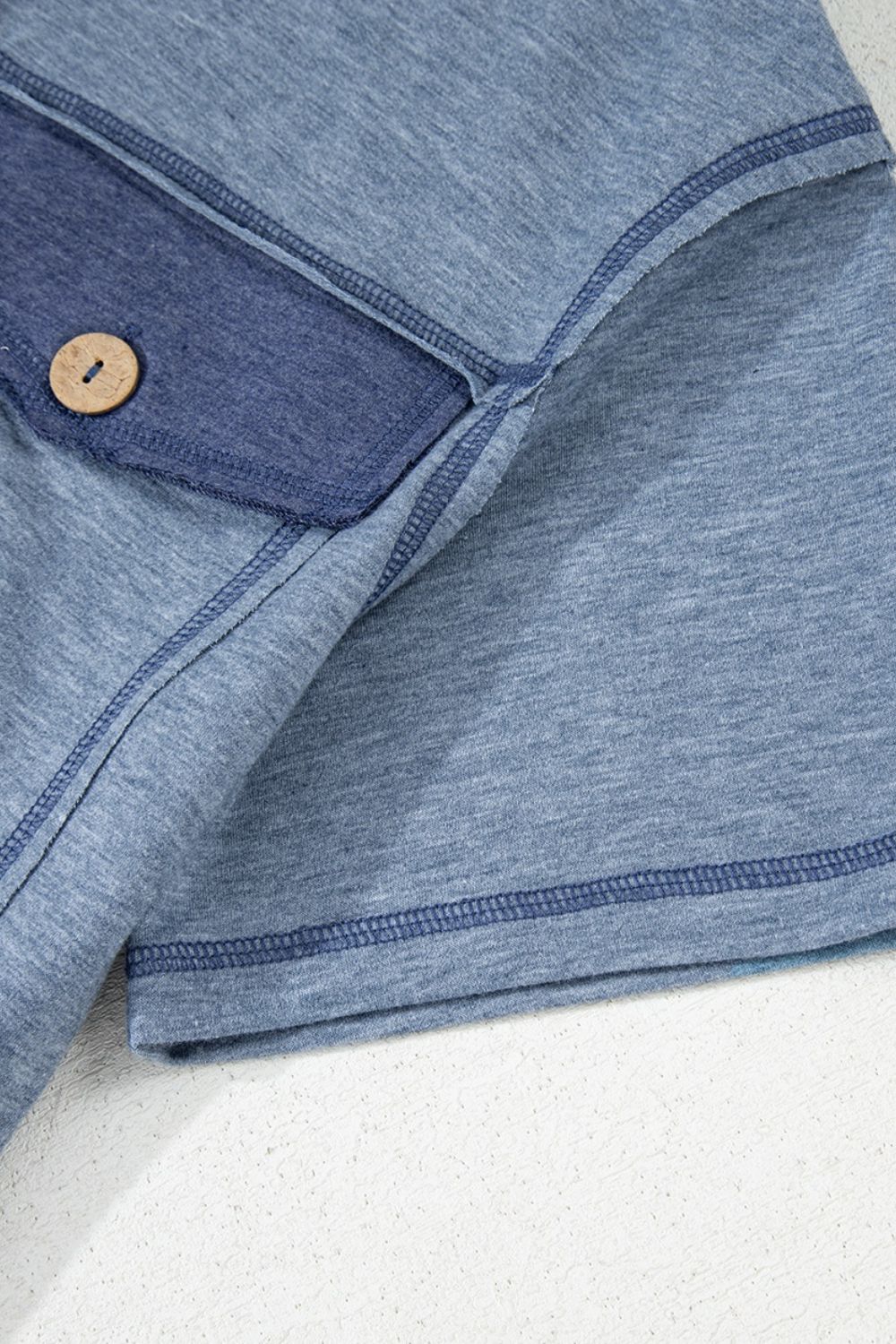 Denim-trimmed utility jumpsuit in dusty blue with a wooden button detail.