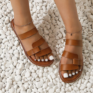 Chic open-toe flat sandals in light brown with toe-ring detail and adjustable straps.