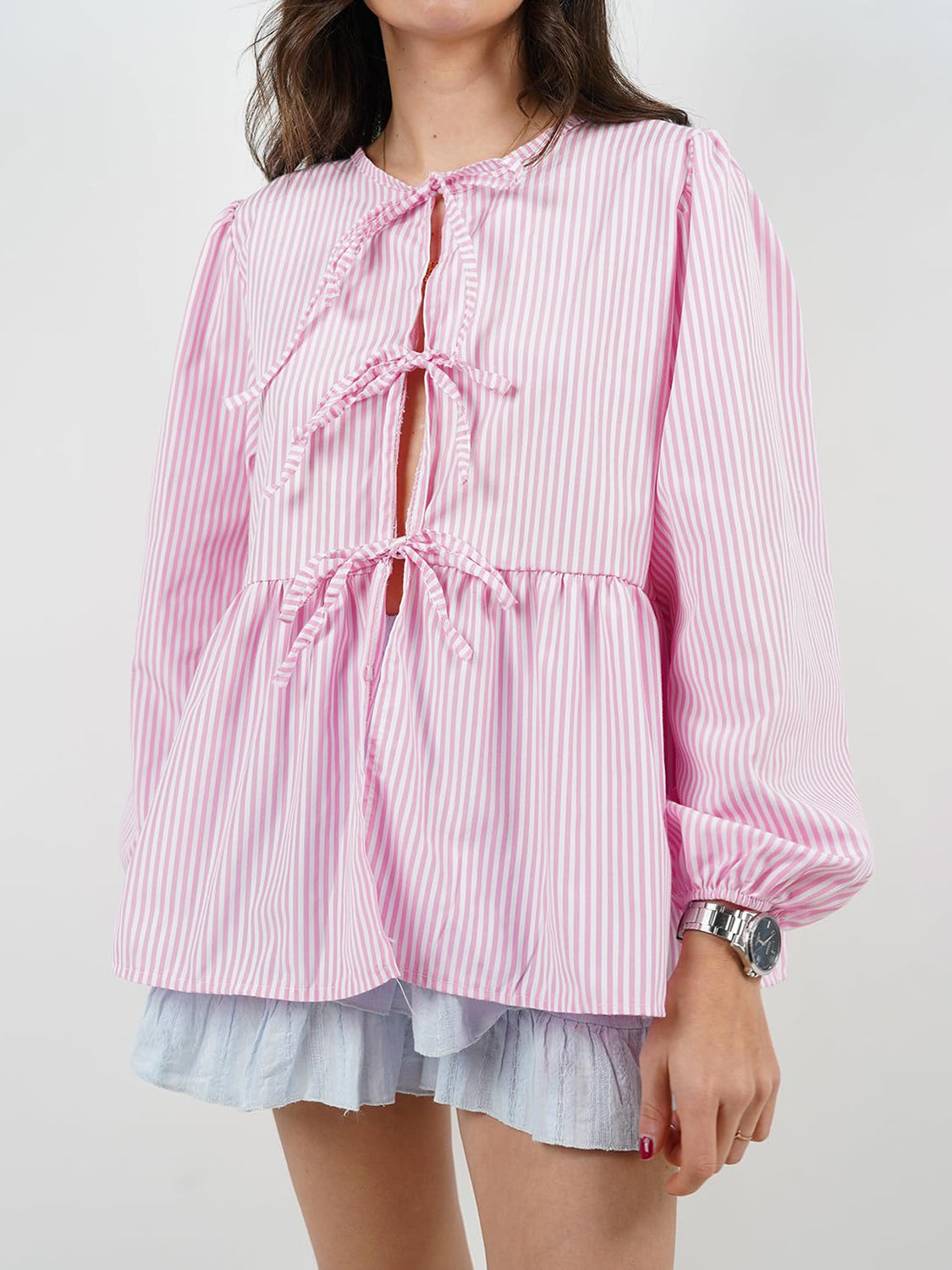 Pink stripe peplum blouse with tie front and voluminous sleeves.