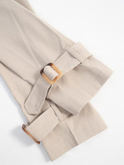 Beige cropped trench coat detail showing adjustable cuffs with tortoise shell buckles.
