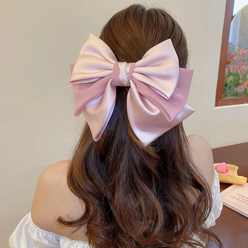 Blush pink satin bow barrette hair accessory with layered bows.
