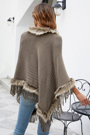 Taupe knit poncho with faux fur trim and fringe detail.