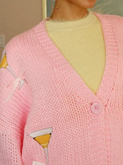 Pink knit cardigan with cocktail glass applique and bow accents, button-up front.