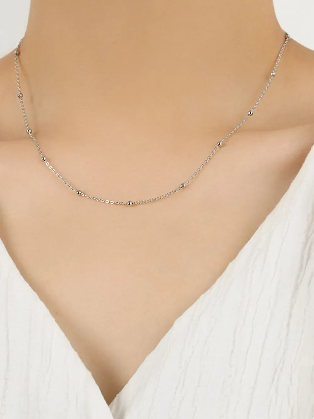 Delicate silver orb chain necklace with small bead accents.