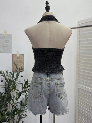 Black denim halter top with smocked bodice and collar, styled with distressed denim shorts.