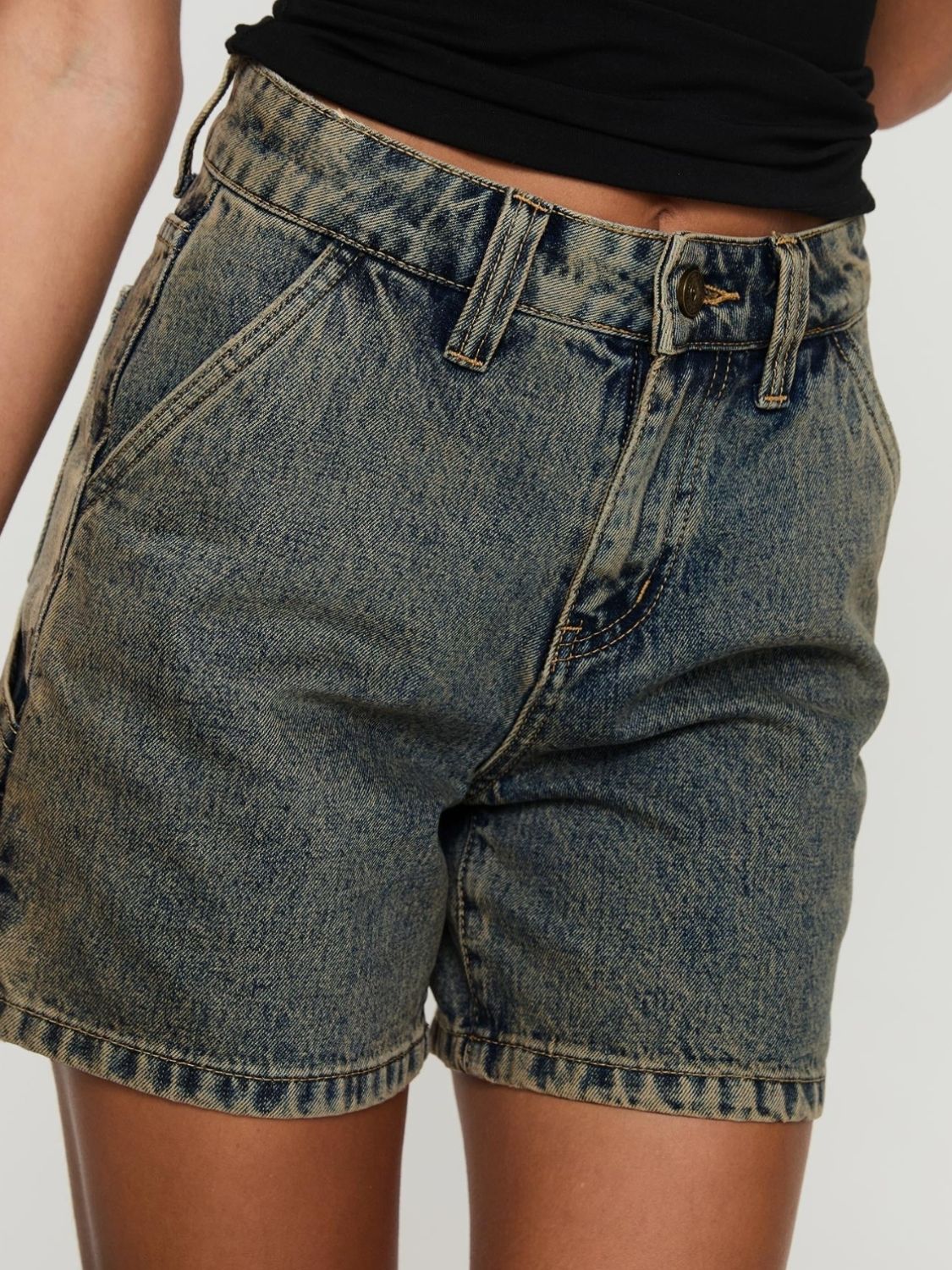Utility denim carpenter shorts in a distressed blue wash with brass button detail.