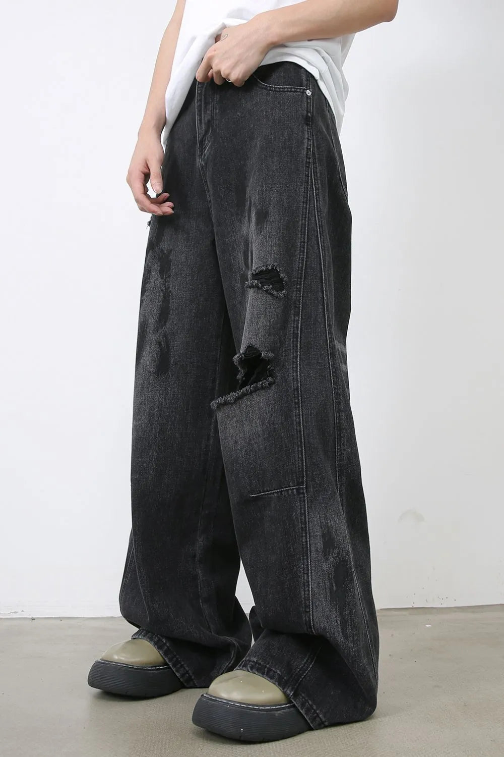 Dark wash relaxed fit denim jeans with distressed rips and wide leg.