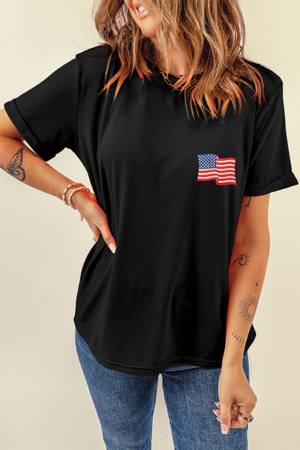 Black t-shirt with rolled sleeves and embroidered American flag detail on chest.