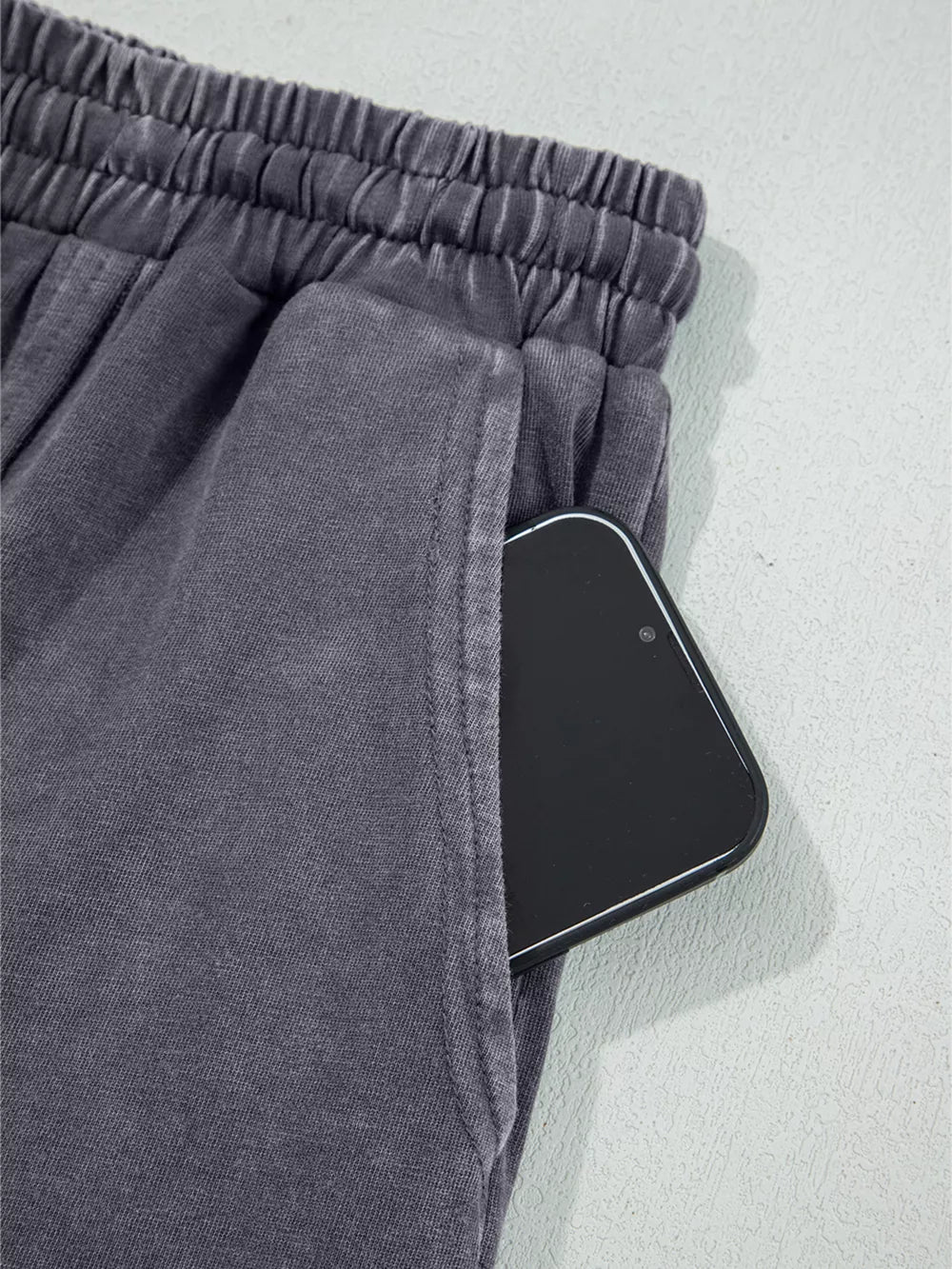 Maternity cropped wide-leg pants in charcoal cotton with elastic waist and side pocket holding a phone.