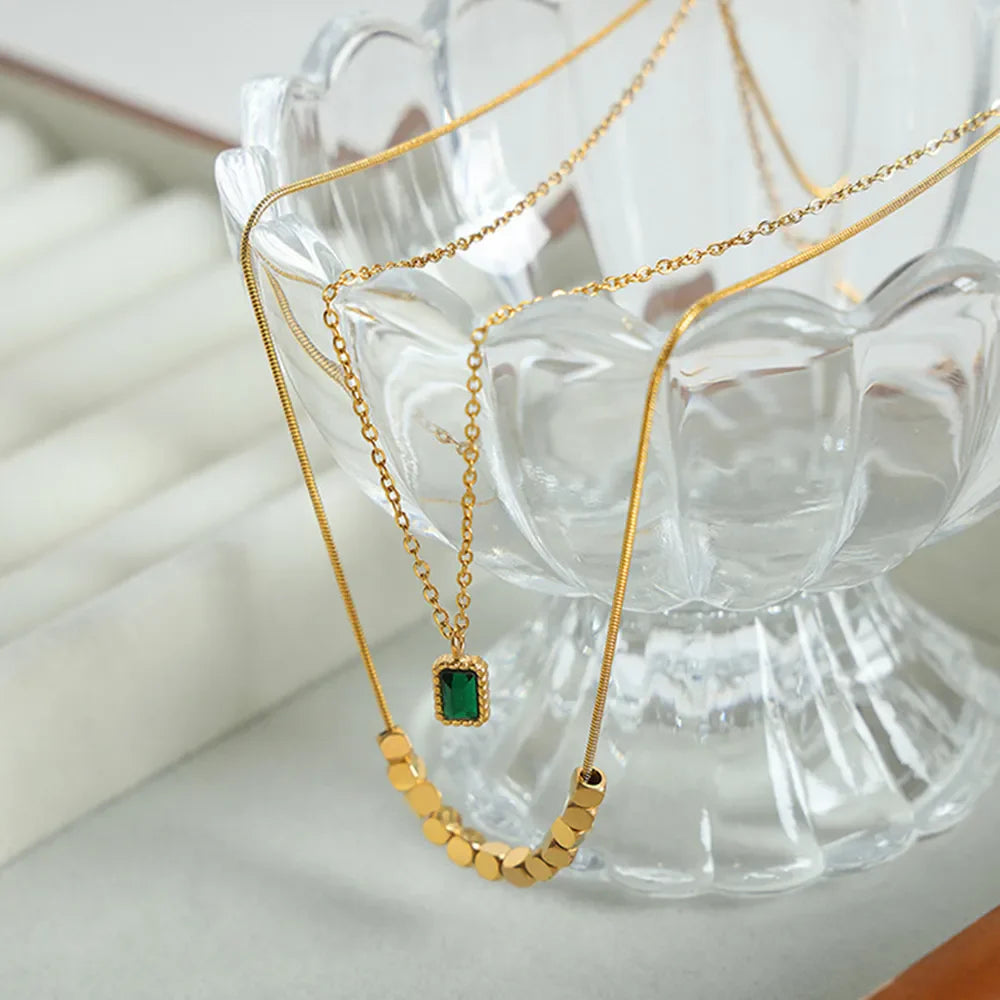 Gold layered necklace with emerald cube pendant and gold bead accents
