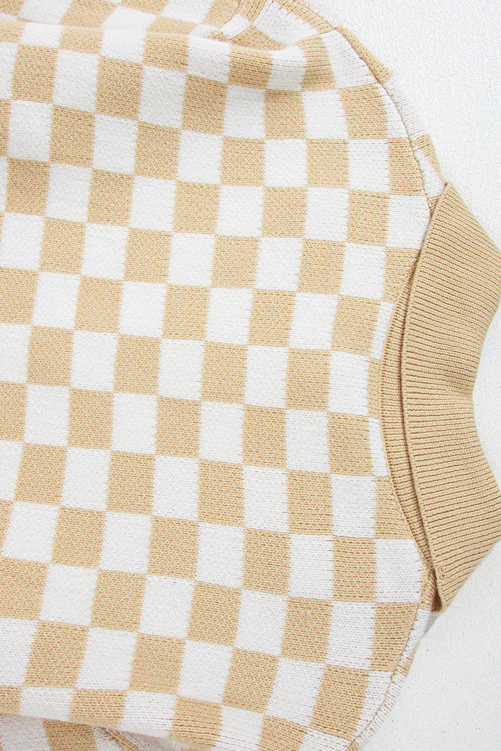 Tan and white checkerboard knit polo sweater with ribbed cuffs.