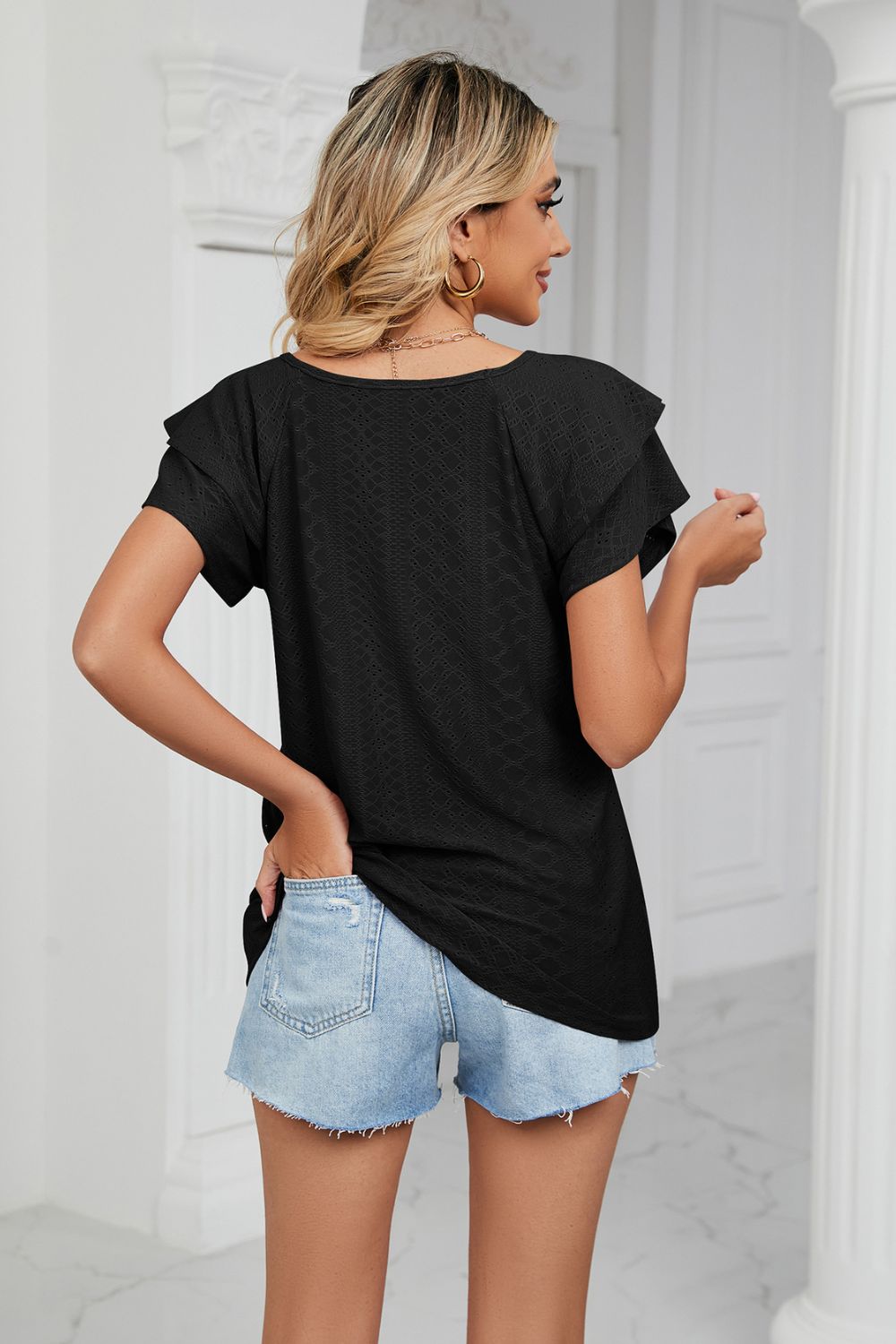 Black eyelet knit blouse with flutter sleeves and v-neck, styled with denim shorts.