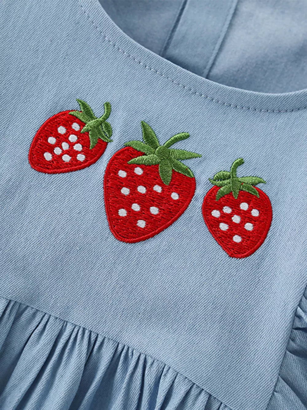 Light blue denim baby dress with embroidered strawberries and ruffled hem.