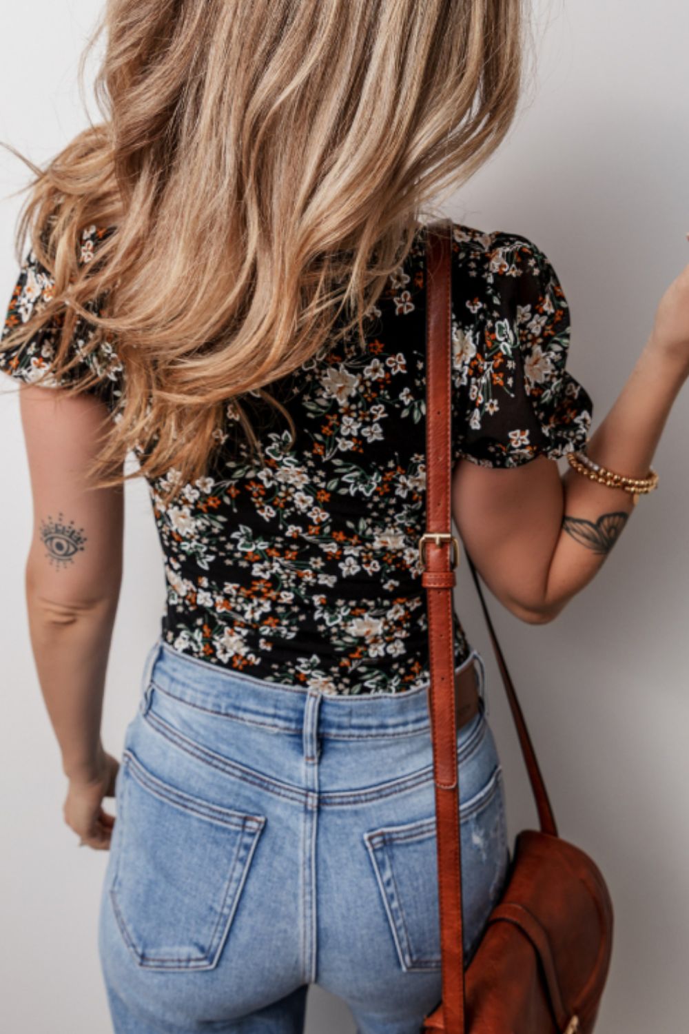 Black floral puff sleeve bodysuit with sheer sleeves, paired with light wash jeans.