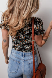 Black floral puff sleeve bodysuit with sheer sleeves, paired with light wash jeans.