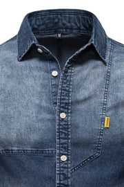 Dark wash denim shirt with asymmetric pocket detail and button-down front.