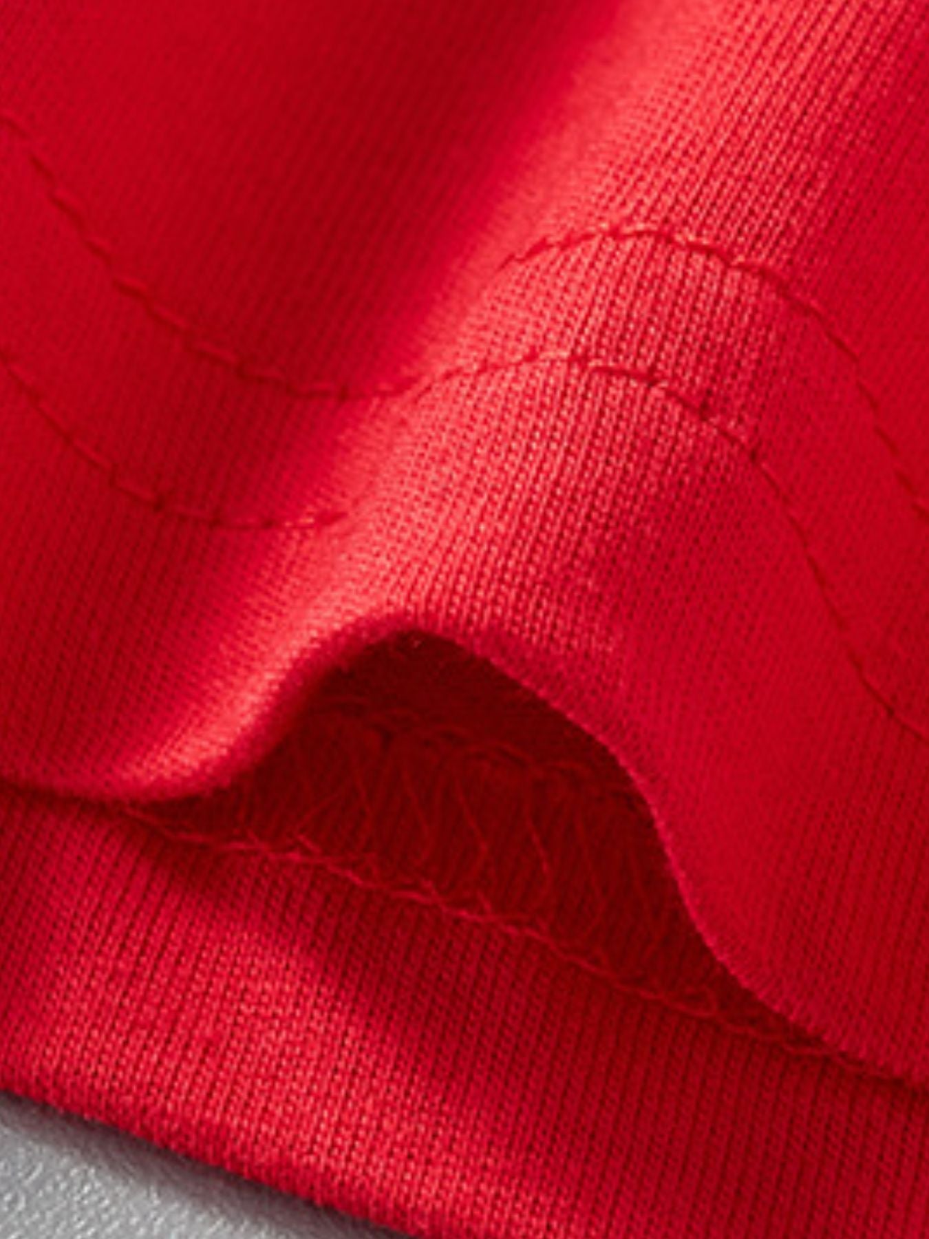 Red cotton t-shirt detail showing fabric texture and stitching.