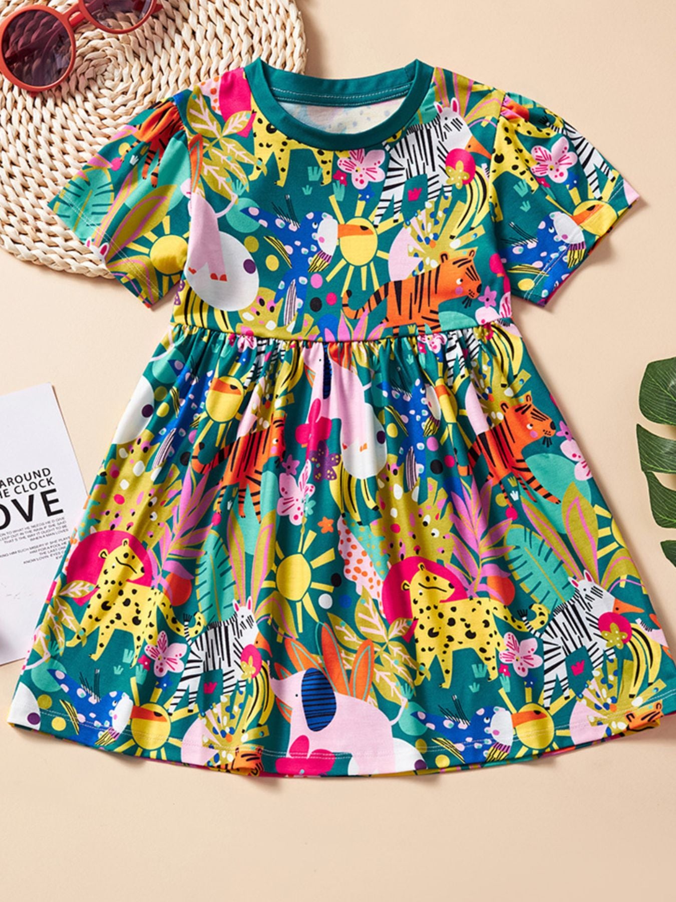 Toddler a-line dress with short sleeves and a playful jungle animal print in green, yellow, pink, and blue.