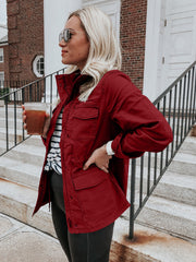 Rust utility jacket with multiple pockets and a stand-up collar, worn casually.