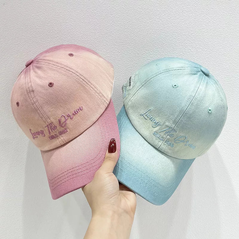 Gradient embroidered cotton baseball caps in peach powder and cyan with embroidered text.