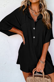 Black oversized shirt romper with button front, chest pocket, and side pockets.