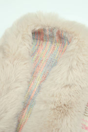 Textured knit cape in tan with a colorful striped lining and plush faux fur collar.